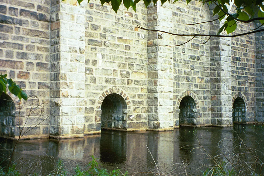 Granite arches of the historic Canton Viaduct reflected in the water below
