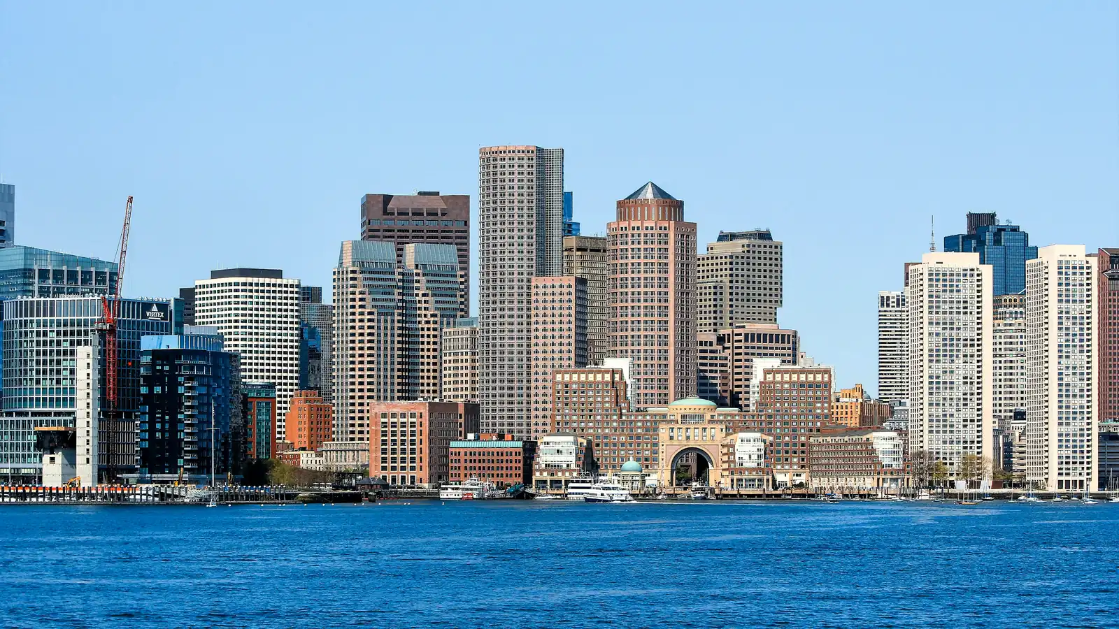 Downtown Boston skyline across the harbor on a clear day, with Rowes Wharf, high-rise towers and new Seaport construction