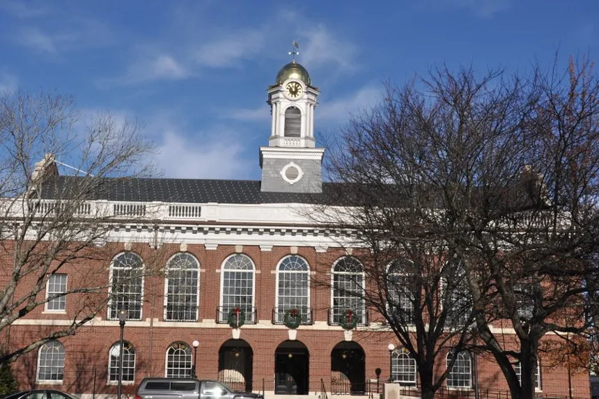 Needham Town Hall, a red-brick building with arched windows and a white clock cupola with a gold dome