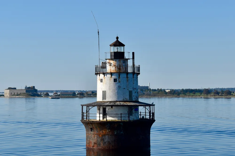 Butler Flats Lighthouse in New Bedford harbor, with Fort Taber on the shoreline behind